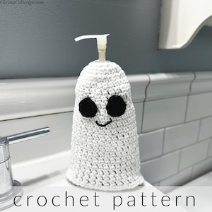 May include: White crocheted ghost soap dispenser with black eyes and a smiling mouth.  The dispenser is sitting on a white tiled counter.  crochet pattern