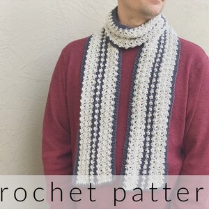 May include: A crochet scarf pattern with alternating stripes of gray and white yarn. The scarf is being worn by a person wearing a maroon sweater.