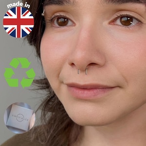 Puede incluir: Primer plano de un rostro con dos piercings de nariz plateados. La imagen incluye un símbolo de reciclaje y una caja con el texto "SIMPLY ALICE". Una pegatina "made in" con la bandera del Reino Unido está en la esquina superior izquierda.