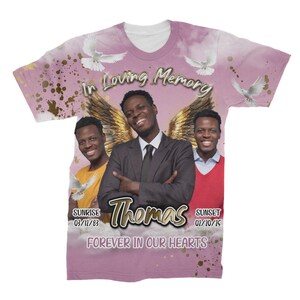 May include: A pink t-shirt with a memorial design featuring three men with angel wings. The text reads "In Loving Memory Thomas" with dates for sunrise and sunset. The text "Forever in Our Hearts" is also included.