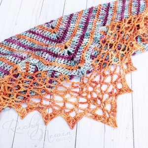 May include: A crocheted shawl with a colorful striped pattern and a lacy orange border. The shawl is made with a variety of colors, including purple, teal, and orange. The lacy border is made with a delicate stitch pattern and has a starburst shape.
