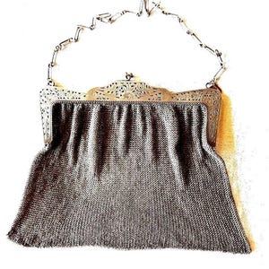Pode incluir: Uma bolsa de mão vintage de malha de metal prateado com uma moldura decorativa e uma alça de corrente. A bolsa tem formato retangular com uma moldura ornamentada. O corpo de malha pende solto, criando um efeito drapeado.