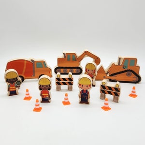 Op de afbeelding: Houten constructiespeelgoedset met een oranje cementwagen, graafmachine en bulldozer. Inclusief houten figuren van bouwvakkers, oranje verkeerskegels en barricades. Eén figuur houdt een "GO"-bord vast.