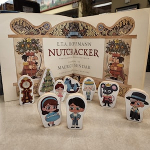 May include: A set of wooden figurines from the Nutcracker story. The figurines include a nutcracker, a mouse king, a ballerina, a soldier, a rocking horse, a Christmas tree, and a clock. The figurines are painted in bright colours and have detailed features.
