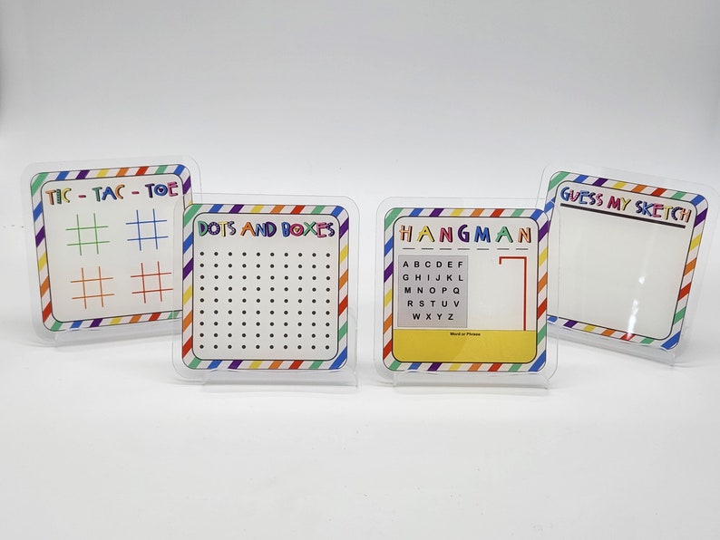 May include: Four colorful dry-erase boards with different games: Tic-Tac-Toe, Dots and Boxes, Hangman, and Guess My Sketch. Each board has a rainbow striped border.