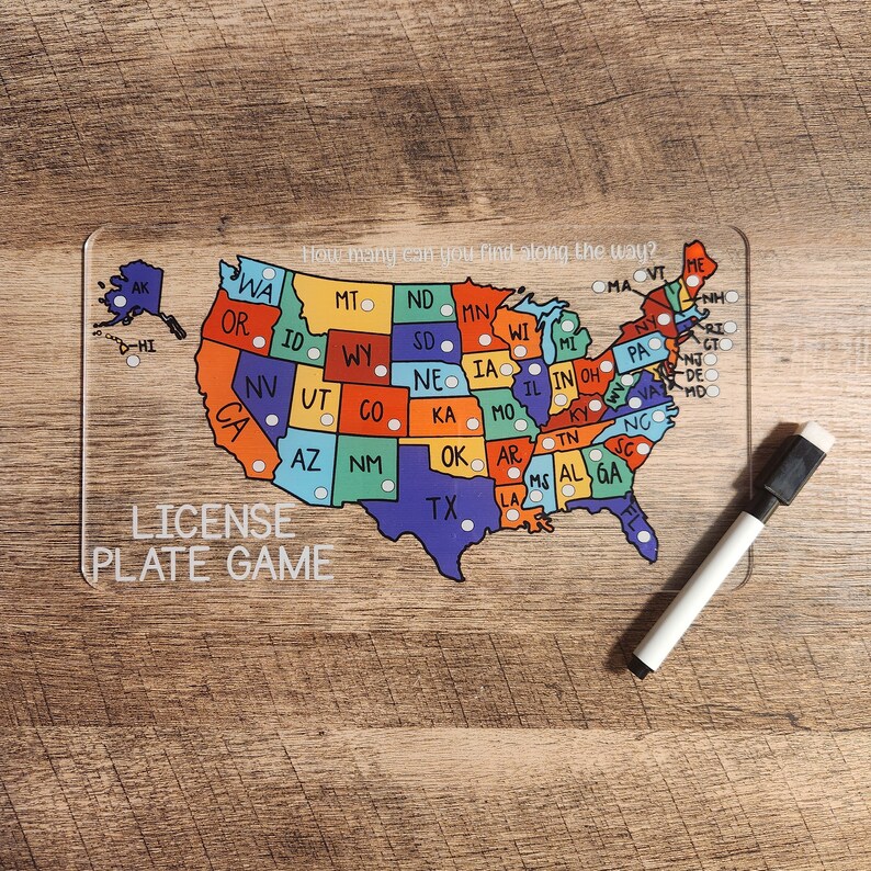 May include: A clear acrylic game board with a map of the United States. Each state is a different color and has a small circle in the center. The text "How many can you find along the way?" is at the top of the board. The text "LICENSE PLATE GAME" is at the bottom of the board.