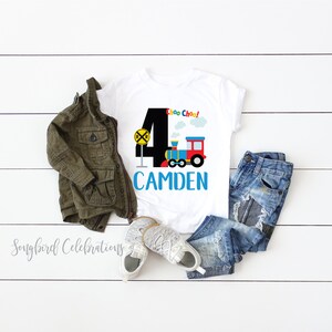 May include: White t-shirt with a black number 4, a colorful train, and the text "Choo Choo!" and "CAMDEN".