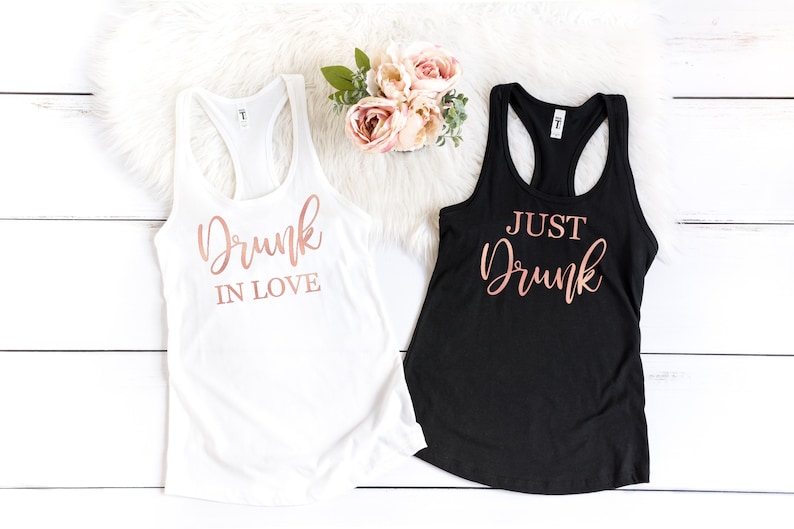 May include: Two tank tops with rose gold lettering. One white tank top says "Drunk in Love" and one black tank top says "Just Drunk".
