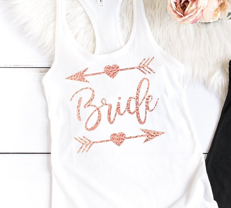 May include: White tank top with a rose gold glitter design that says "Bride" with arrows and hearts.