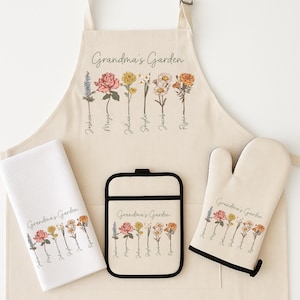 May include: A beige kitchen set including an apron, oven mitt, pot holder, and towel, all with a floral design. The text "Grandma's Garden" is printed on each item, along with names and flower illustrations. The apron measures approximately 76 cm in length.
