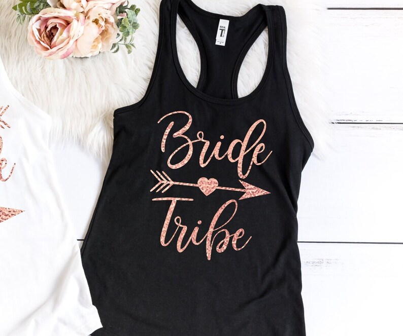 May include: Black tank top with a rose gold glitter design that says "Bride Tribe" with an arrow and heart.