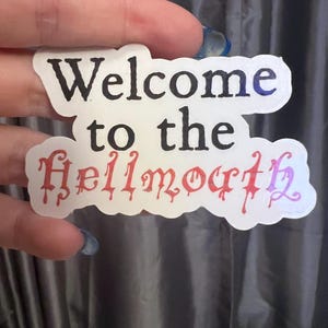 May include: White sticker with the text "Welcome to the Hellmouth" in black and red lettering. The text "Hellmouth" is in a dripping font.