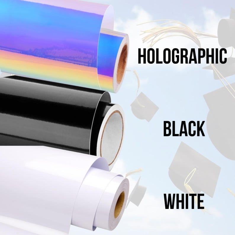 May include: Three rolls of vinyl adhesive film in holographic, black, and white colours. The rolls are partially unrolled and the ends are visible. The background is a blurry image of a blue sky with white clouds.