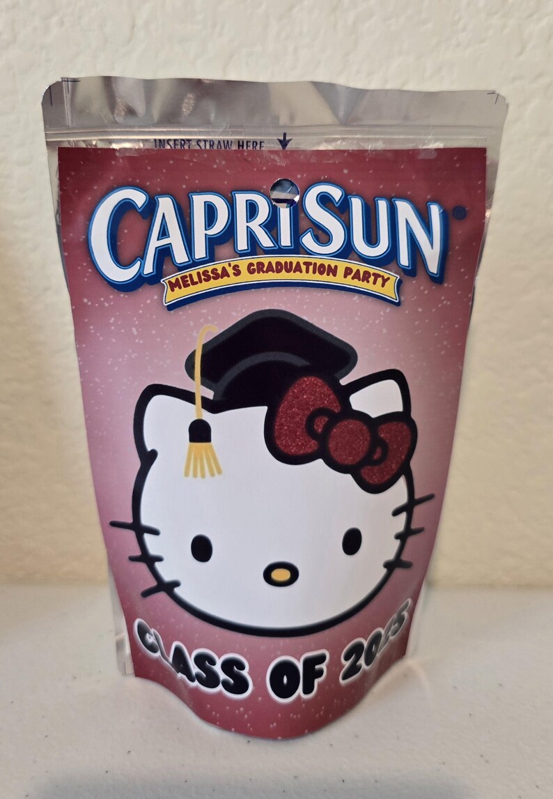 May include: A pink Capri Sun juice pouch with a Hello Kitty design. Hello Kitty is wearing a graduation cap and a red bow. The text "Melissa's Graduation Party" and "Class of 2015" are printed on the pouch.
