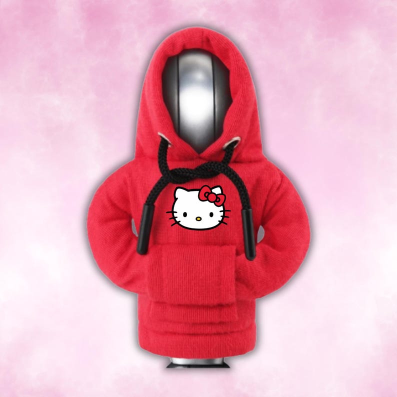 May include: Red hooded sweatshirt with a black drawstring and a white Hello Kitty graphic on the front.