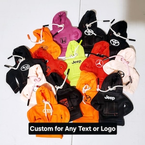 May include: A collection of colorful mini hoodies with various logos and text, including "Jeep", "Honda", and car emblems. The hoodies are made of soft, plush fabric and are perfect for adding a touch of personality to your car or home decor. Custom for Any Text or Logo.