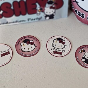May include: Four round stickers with a Hello Kitty design. The stickers are pink and white with a black outline. The stickers feature Hello Kitty wearing a graduation cap and gown. The text on the stickers reads "Class of 2025" and "Thank you for coming to Melissa's Graduation Party".