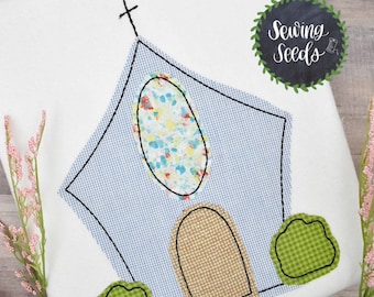 May include: Embroidered applique design of a blue church with a stained glass window, a brown door, and green bushes. The design is perfect for sewing projects.