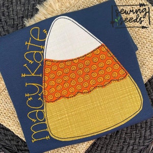 Könnte beinhalten: Ein marineblaues T-Shirt mit einem gelben und orangefarbenen Mais-Applikationen. Der Text "macy kate" ist in Gelb auf der linken Seite des Shirts gestickt.