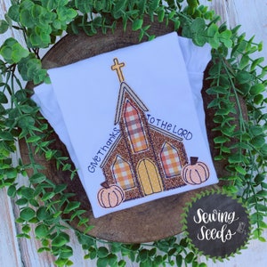 May include: Embroidered design of a church with a cross on top, two pumpkins, and the text "Give Thanks to the Lord".