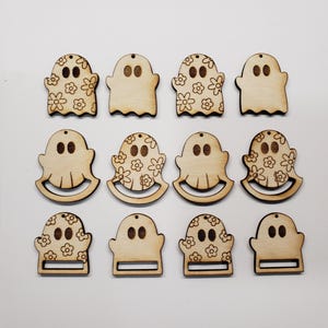 Könnte beinhalten: Zwölf Holzornamente in Geisterform. Einige Geister haben ein Blumenmuster, andere sind schlicht. Jedes hat ein kleines Loch zum Aufhängen. Die Ornamente sind hellbraun und eignen sich für Halloween oder Bastelprojekte.