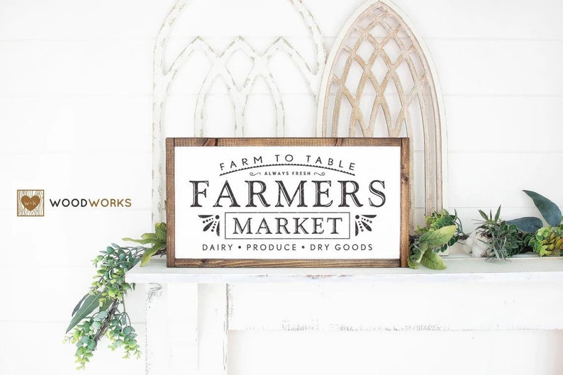 May include: A wooden sign with the text "Farm to Table Always Fresh Farmers Market Dairy Produce Dry Goods" in black lettering on a white background.