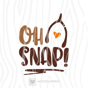 May include: Brown and orange graphic design with the text "Oh Snap!" and a broken wishbone with a heart in the middle. The text "Woodworks" is at the bottom of the design.