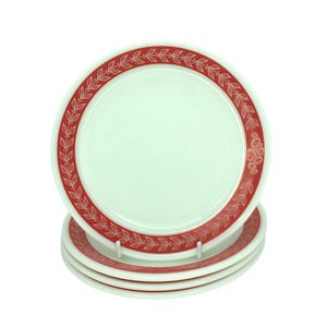May include: A stack of white ceramic plates with a red leaf and floral border design. The plates are stacked, with the top plate facing the viewer. The plates are clean and appear unused. Each plate has a diameter of approximately 23 cm.