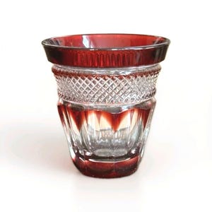 May include: A white ceramic mug with a black handle and the text "But First, Coffee" in a bold, black font. The mug is set against a blurred background, suggesting a cozy setting. The mug appears to be approximately 4 inches tall.