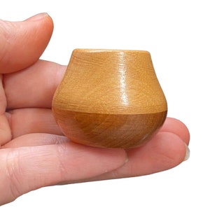 Könnte beinhalten: Eine kleine, braune Holzschale mit abgerundetem Boden und leicht ausgestelltem Rand.