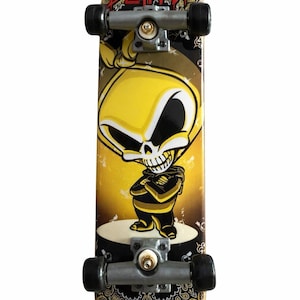 May include: A skateboard featuring a yellow skull graphic and the word "BLIND" in red. The deck has a black and gold paisley pattern. The wheels and trucks are silver and black.