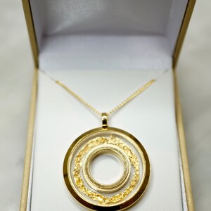 May include: A gold pendant necklace with a circular design, presented in a white box. The pendant features three concentric circles, with the middle circle filled with gold flakes. The box is labeled "Australian Gold".