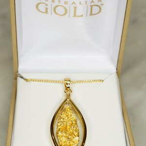 May include: A gold necklace with a pendant featuring a leaf-shaped design filled with real Australian gold flakes. The pendant is in a white box with the words "Australian Gold" printed on the box.