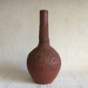 May include: A terracotta vase with a dragon design. The vase has a wide base and a long, narrow neck.