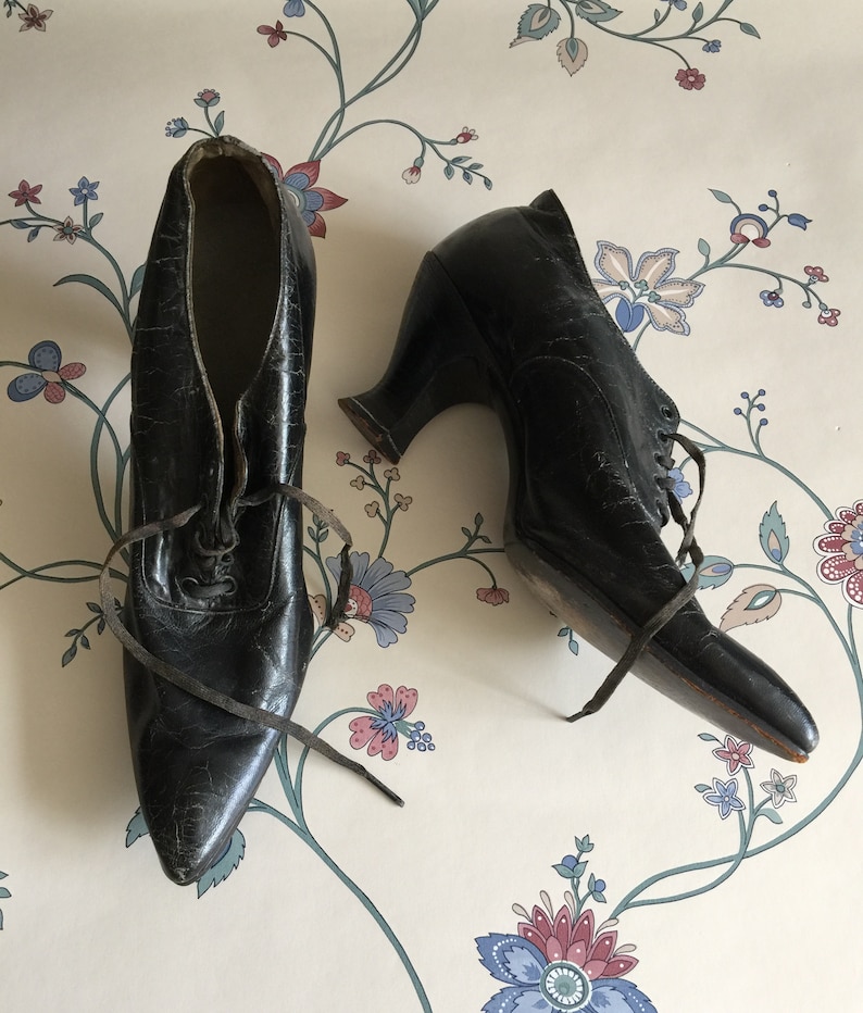 May include: A pair of black leather heeled shoes with lace-up fronts. The shoes have a pointed toe and a high heel.