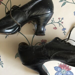 May include: A pair of black leather lace-up shoes with a low heel. The shoes have a vintage look and are in good condition.