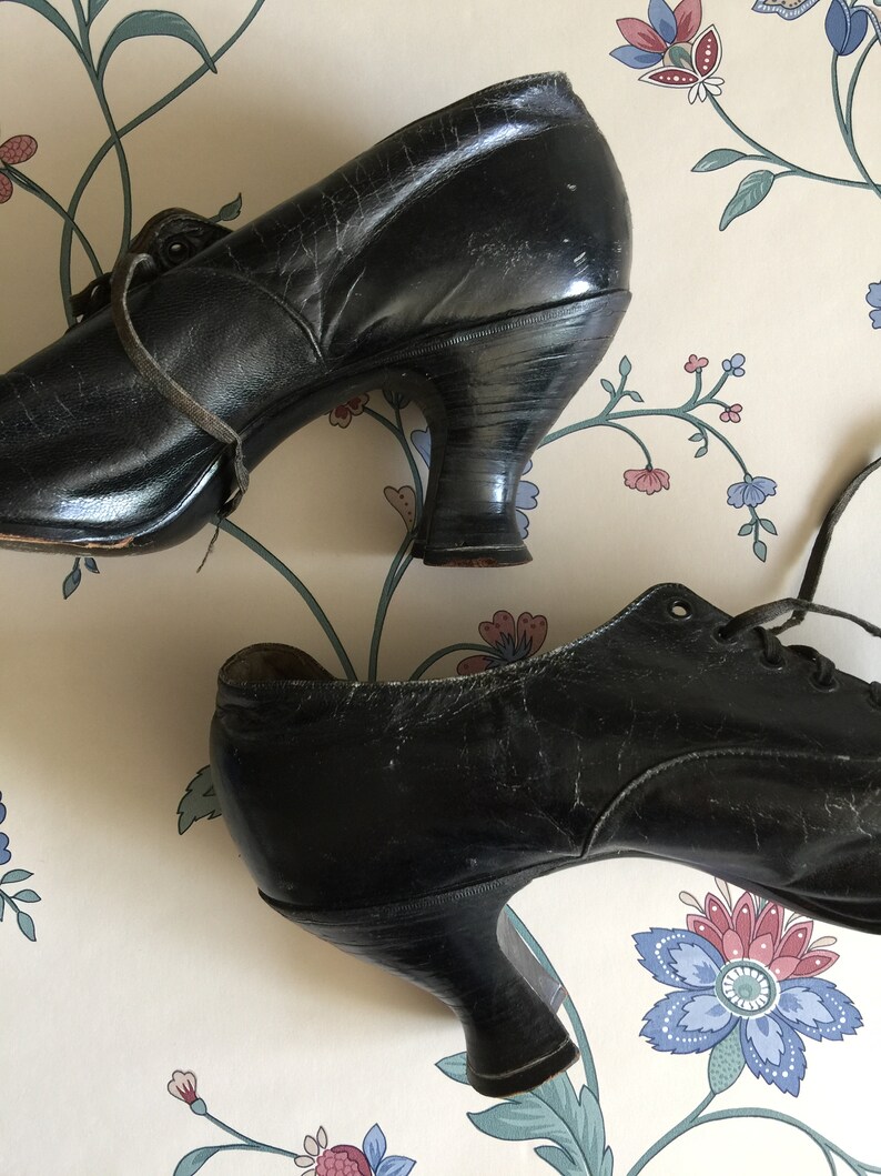 May include: A pair of black leather lace-up shoes with a low heel. The shoes have a vintage look and are in good condition.