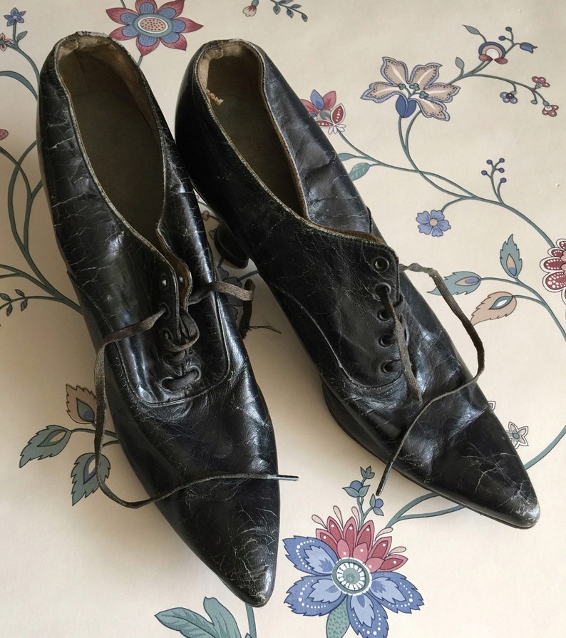 May include: A pair of black leather pointed-toe shoes with lace-up fronts. The shoes have a vintage look and are in good condition.
