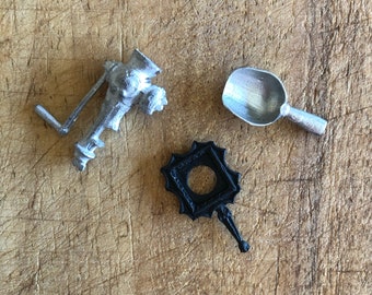May include: Three miniature metal objects: a silver hand crank grinder, a black picture frame, and a silver scoop.