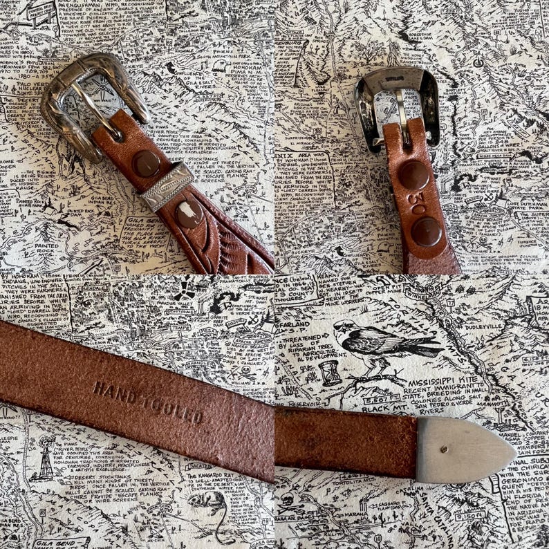 May include: A collection of brown leather belts with silver buckles and hardware. One belt is stamped "HAND TOOLED". The belts are displayed on a map-themed background. The belts have a western or vintage aesthetic.