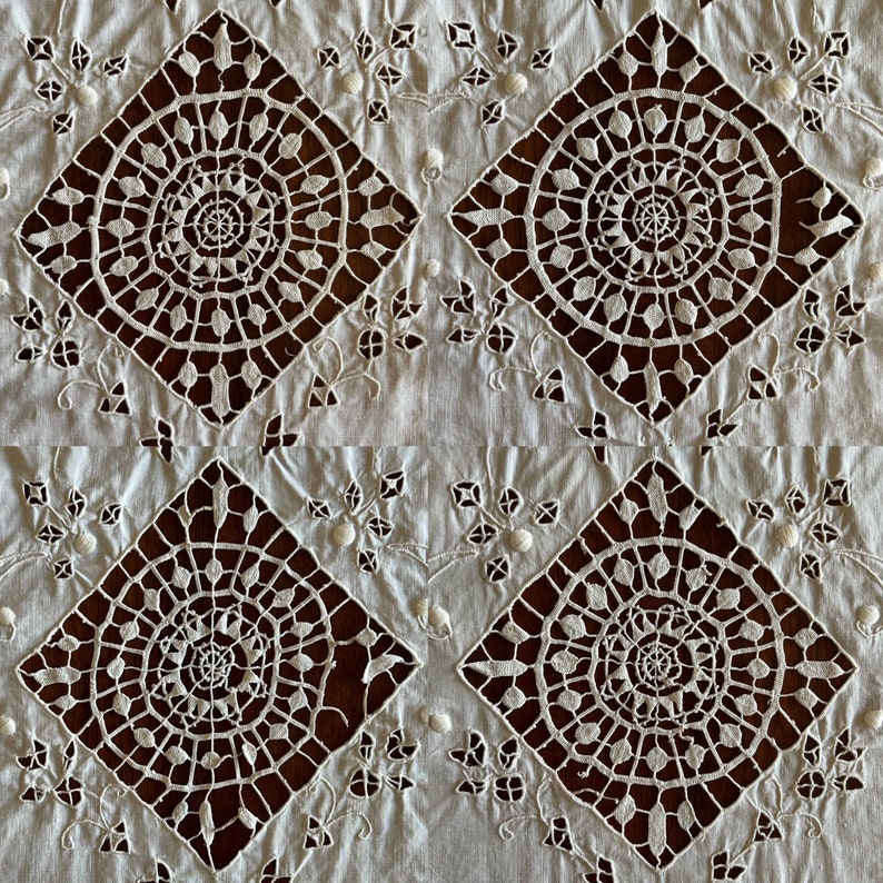 May include: White cotton fabric with a repeating pattern of intricate, cut-out lace designs. The lace features a circular motif with a central spiral and radiating lines.