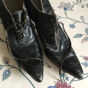 May include: A pair of black leather shoes with pointed toes and lace-up fronts. The shoes have a worn, vintage look.