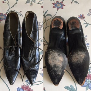 May include: A pair of black leather heeled shoes with pointed toes and lace-up fronts. The shoes have a worn look and are in good condition.