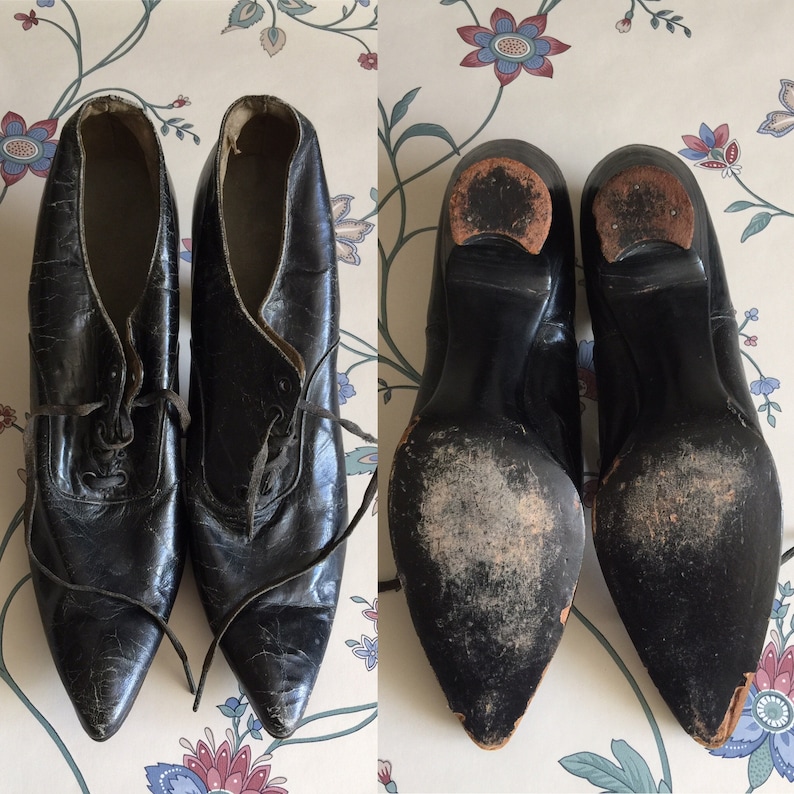 May include: A pair of black leather heeled shoes with pointed toes and lace-up fronts. The shoes have a worn look and are in good condition.
