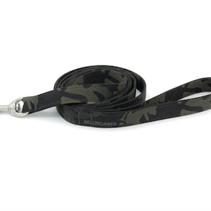 May include: A black and green camouflage dog leash with a silver clip and the word "MULTICAM" printed on the leash.