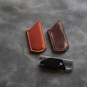 May include: Two leather pouches with stitched edges, one brown and one dark brown, and a black multi-tool with a bottle opener.