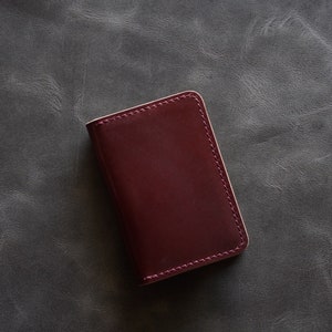 May include: A burgundy leather wallet with a stitched edge.