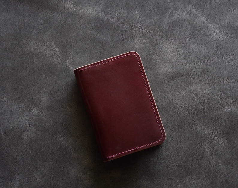 May include: A burgundy leather wallet with a stitched edge.