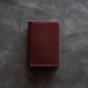 May include: A burgundy leather wallet with a stitched edge.