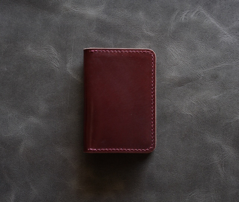 May include: A burgundy leather wallet with a stitched edge.